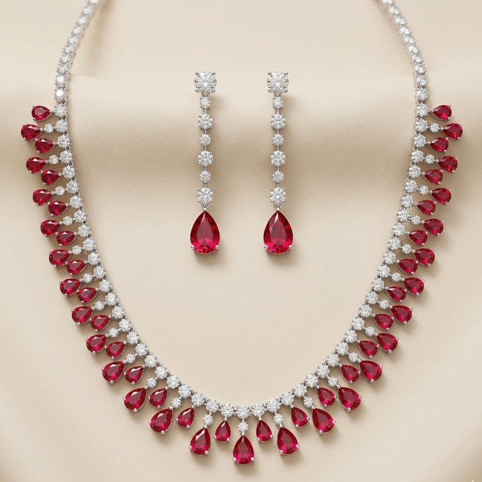 Jewelry set with red gemstones and silver accents on a beige background